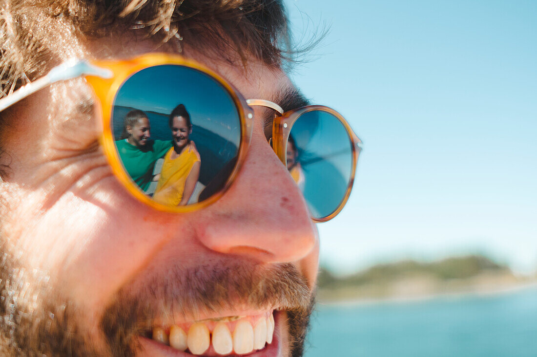 Women reflecting in mans sunglasses