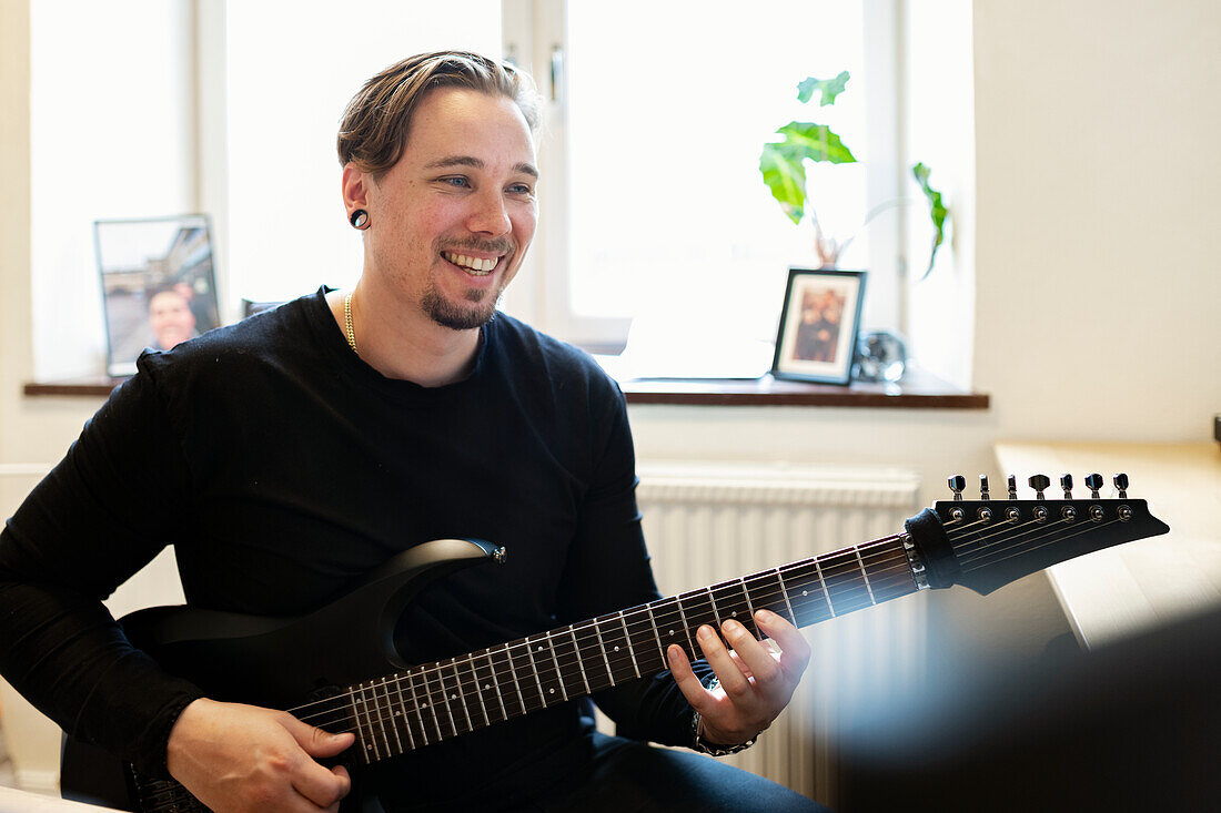 Smiling man playing electric guitar