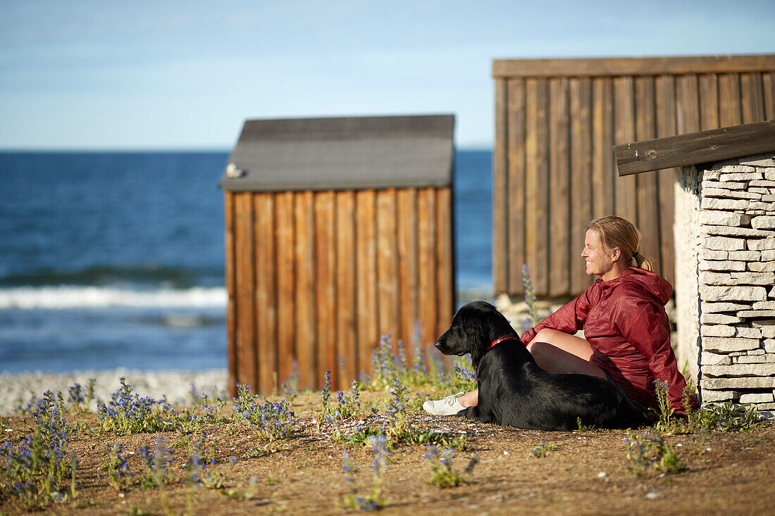 Frau mit Hund sitzend am Meer