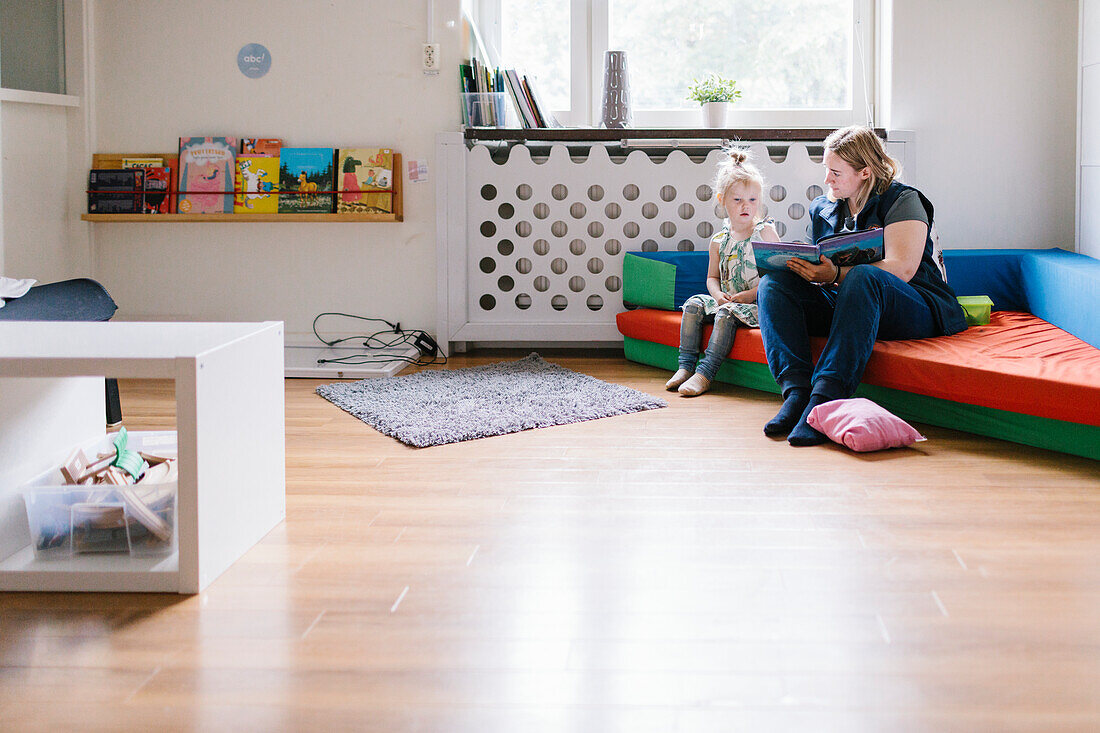 Lehrerin liest einem Mädchen im Kindergarten vor