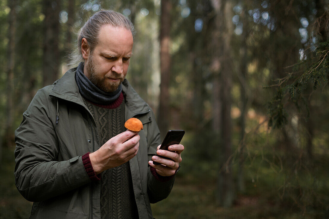 Man holding mushroom and cell phone