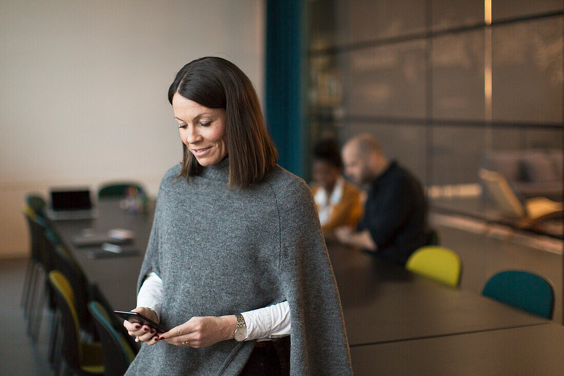 Businesswoman using phone in boardroom