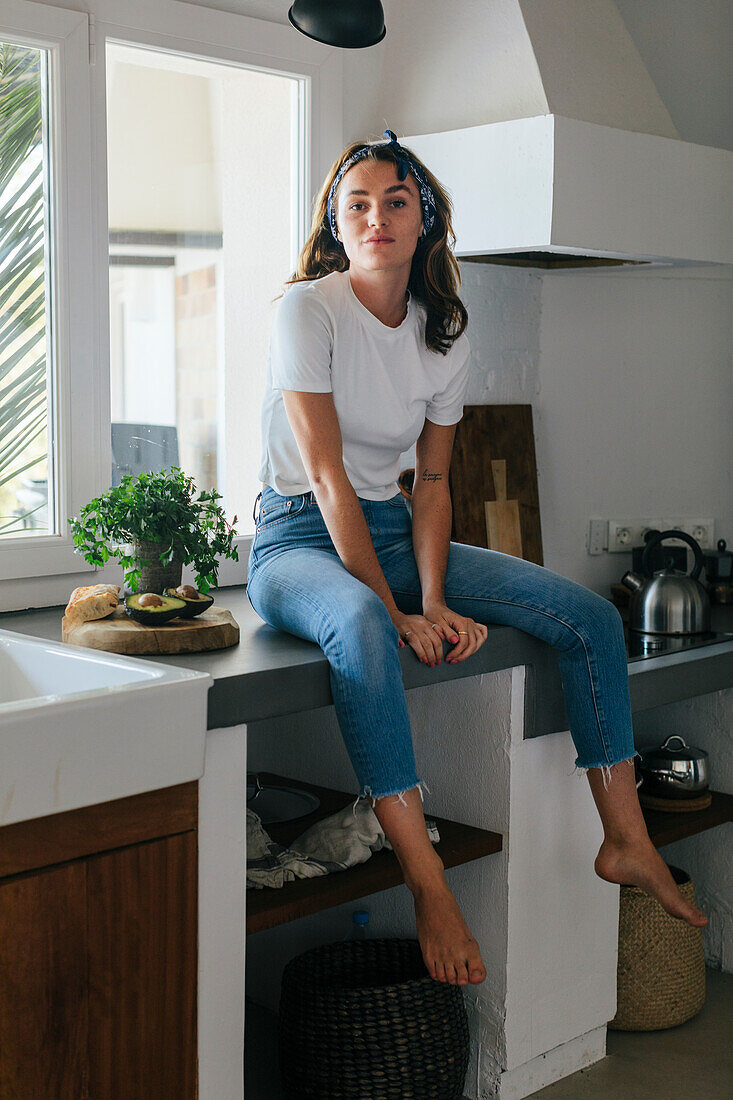 Woman sitting on kitchen worktop