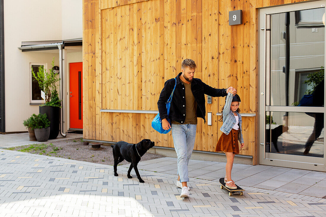 Girl on skateboard holding fathers hand