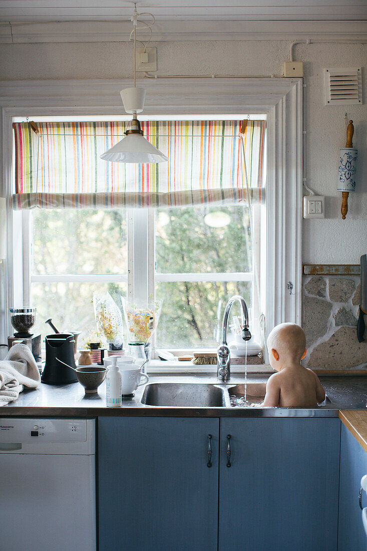 Baby having wash in sink