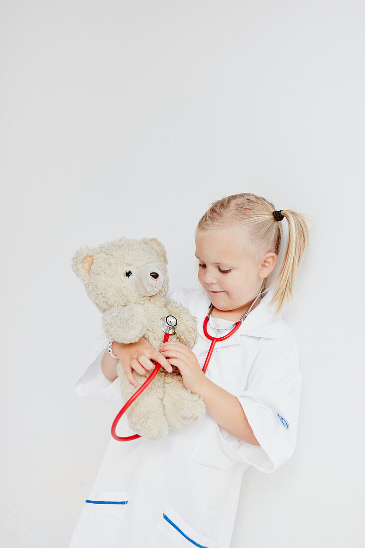 Girl playing doctor with teddy bear