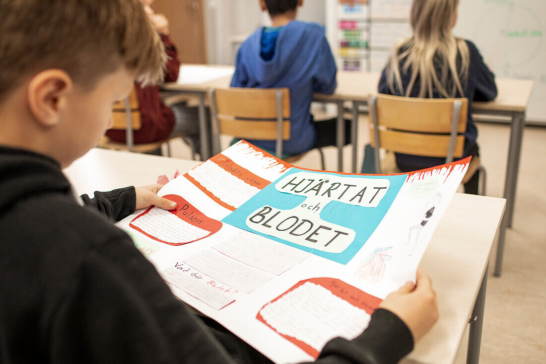 Boy in class holding poster