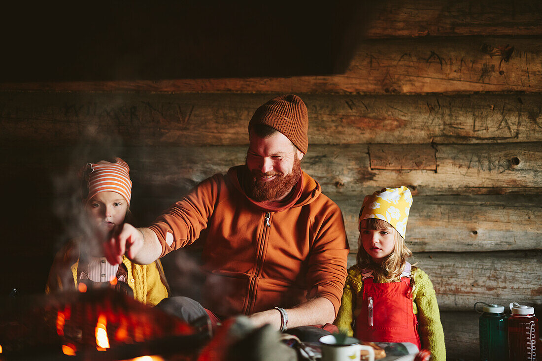 Man with daughters sitting near campfire