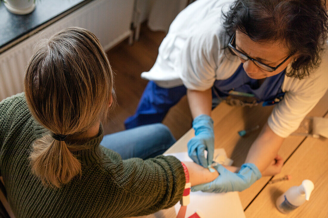 Female nurse is taking blood of patient