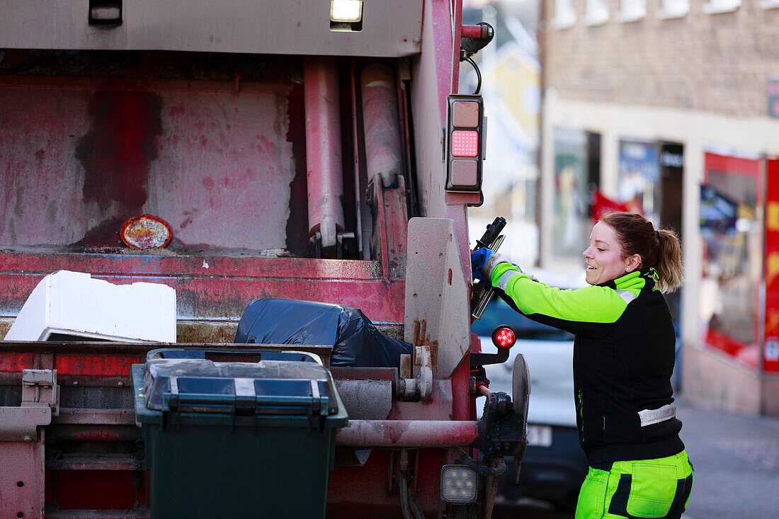Frau bedient Müllwagen
