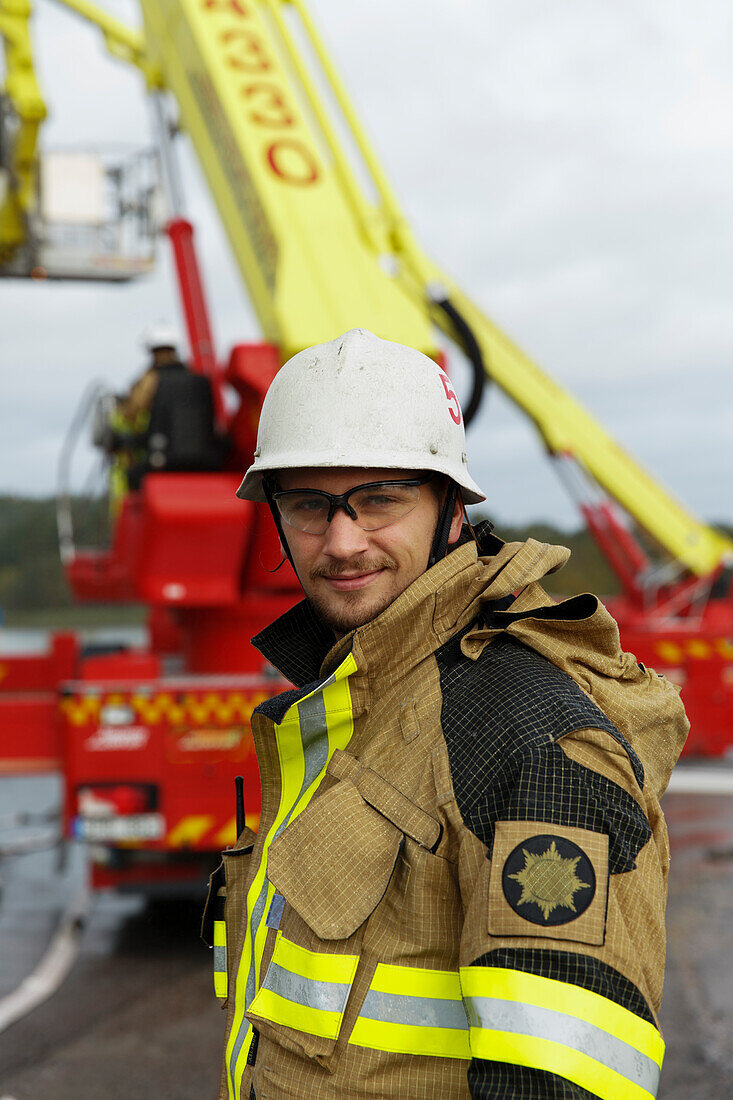 Porträt eines jungen Feuerwehrmanns, Feuerwehrauto im Hintergrund