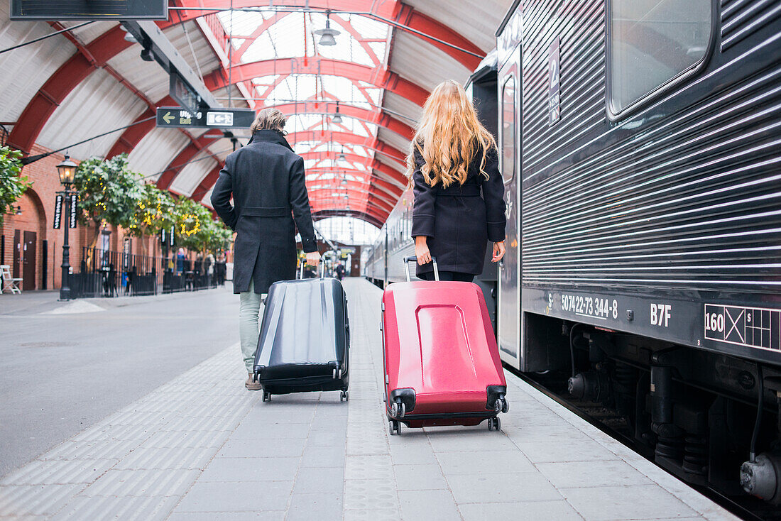 Couple pulling suitcases on train station