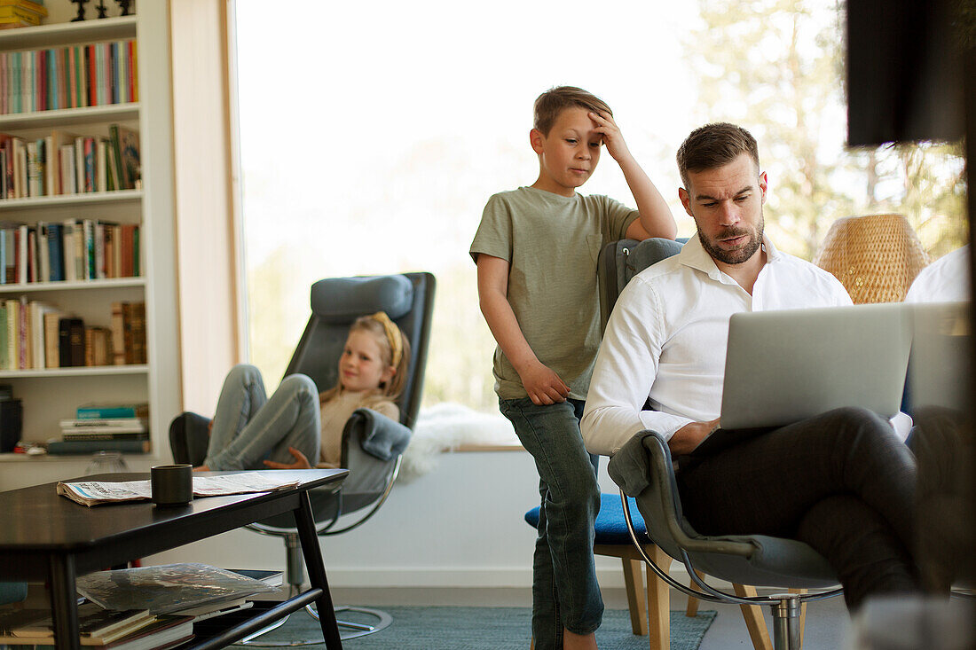 Junge schaut auf Laptop über Vaters Schulter