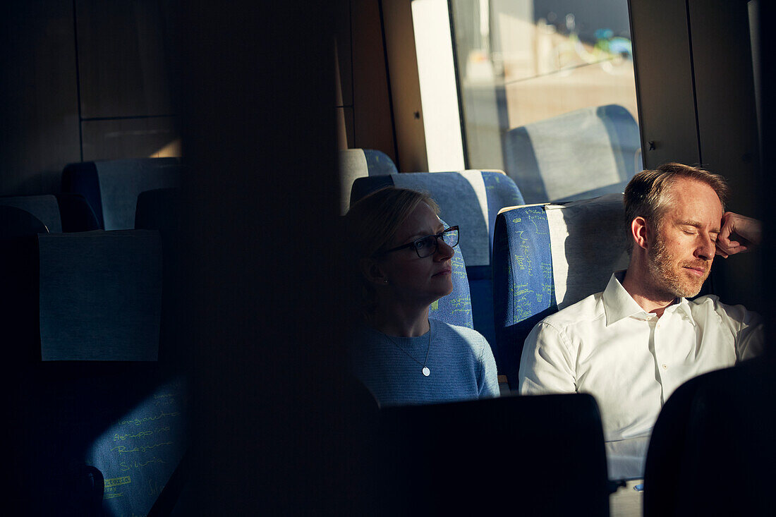 Mann im Zug sitzend mit geschlossenen Augen