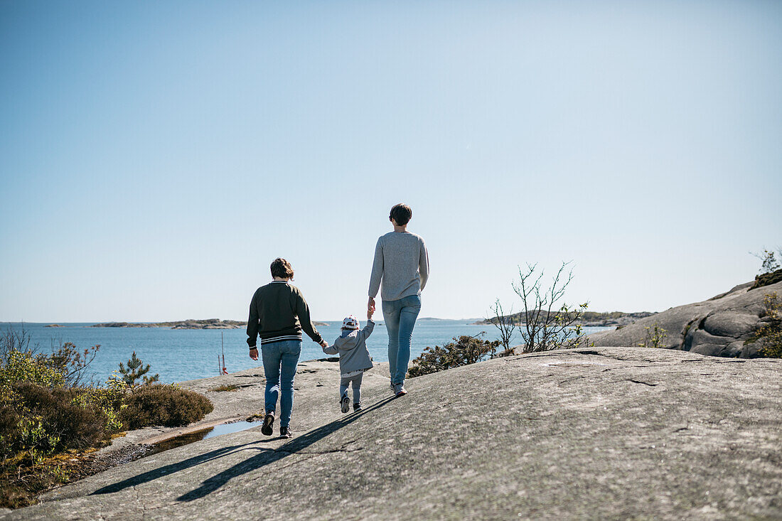 Mothers walking with daughter on coast