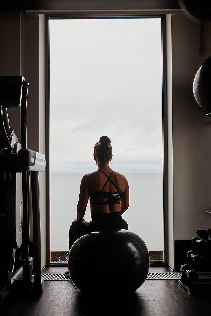 Woman on fitness ball looking through window