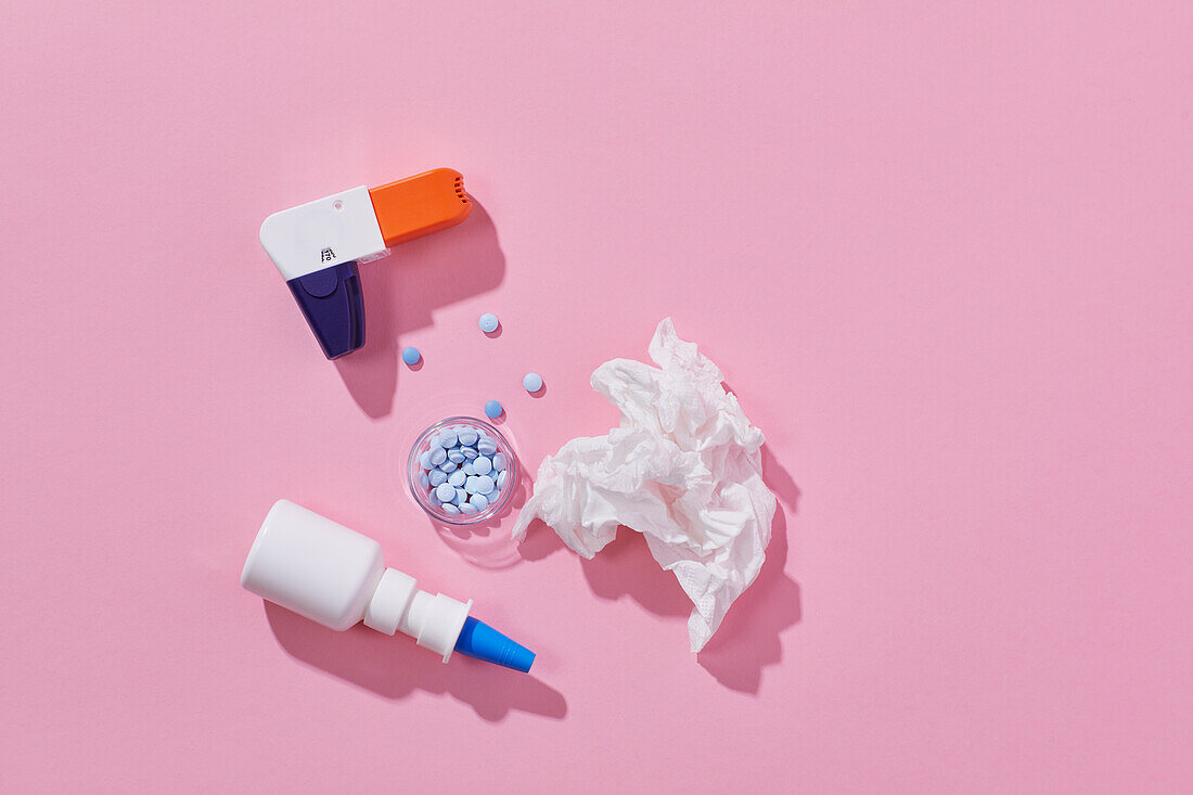 Inhaler and allergy medicine on pink background