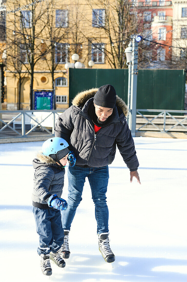Vater bringt seinem Sohn das Schlittschuhlaufen bei