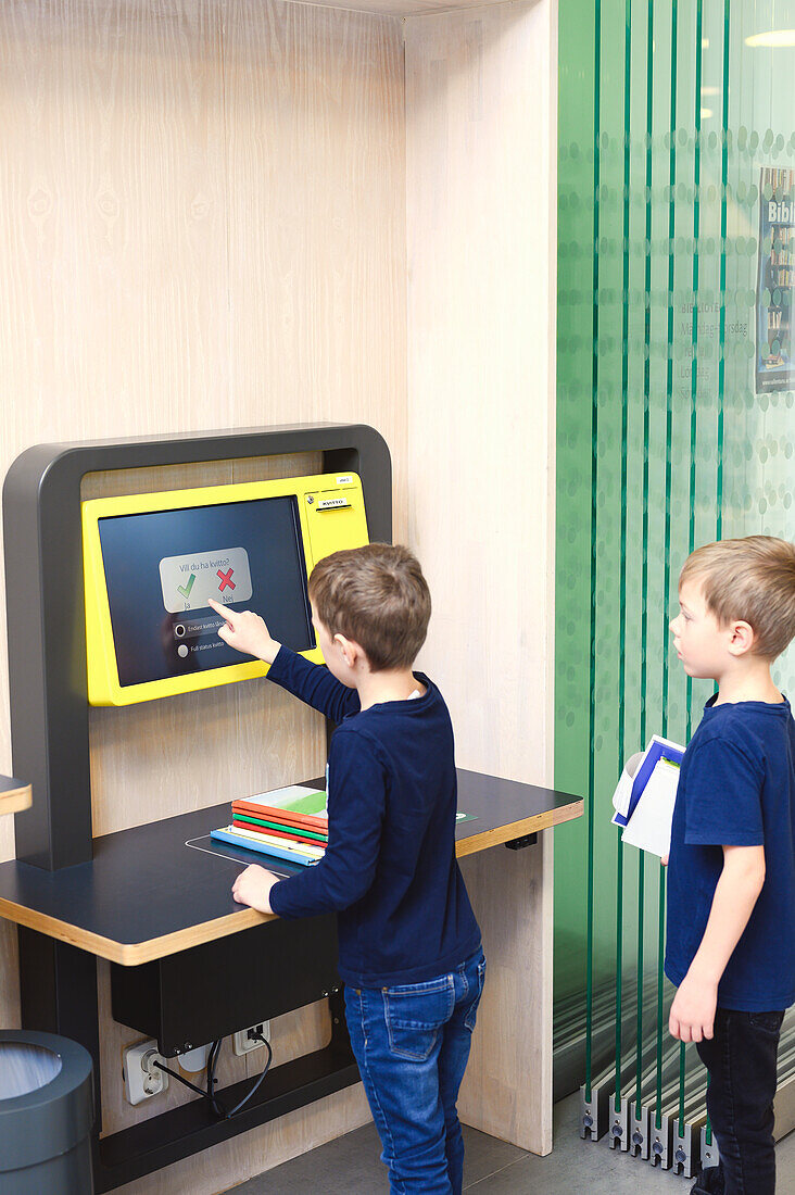 Boys using self service point in library