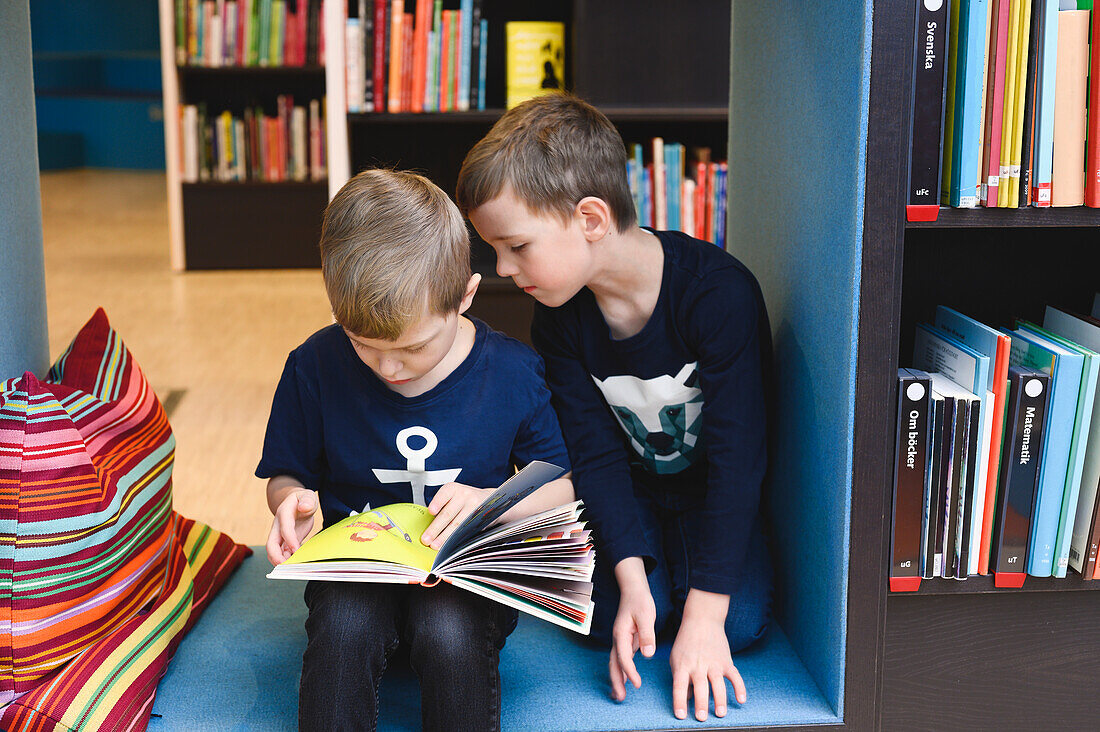 Boys looking at book in library