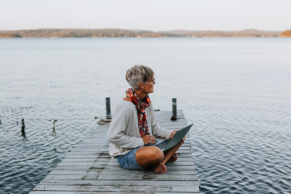 Woman on jetty using laptop