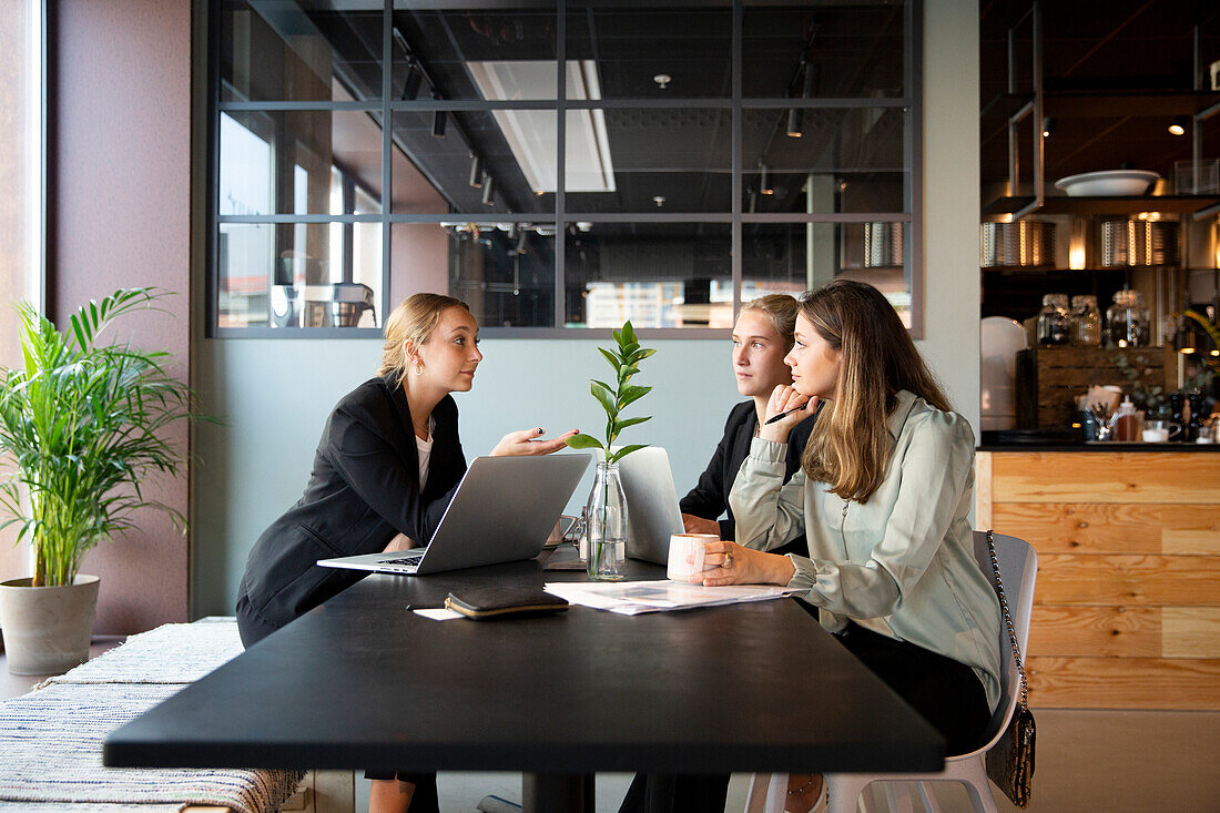 Female coworkers talking in cafe