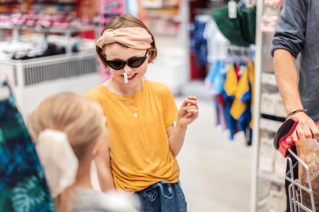 Lächelndes Mädchen probiert Sonnenbrille im Laden