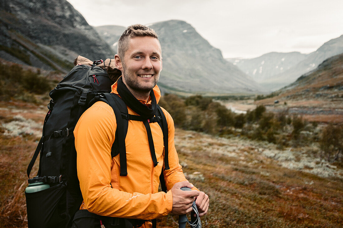 Smiling man carrying backpack in mountains
