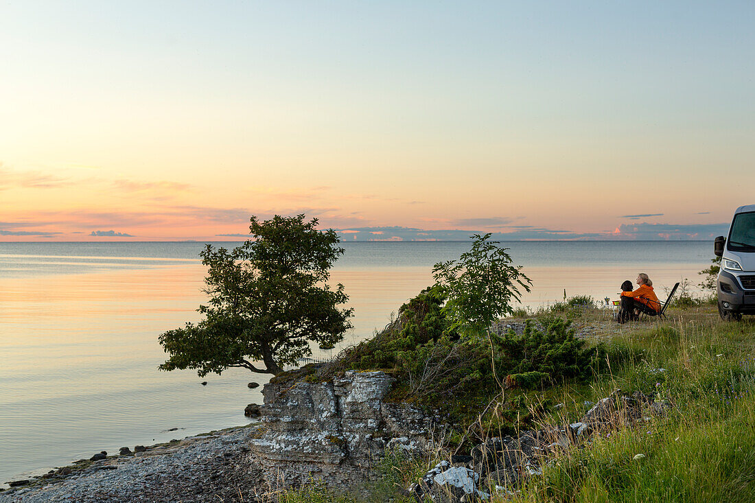 Frau mit Blick auf Sonnenuntergang am Meer