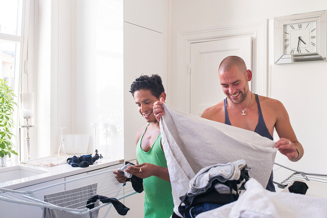 Male couple folding laundry at home