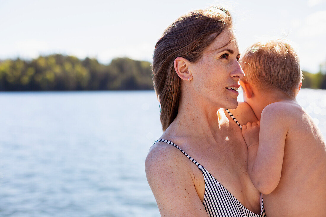 Woman at lake carrying son