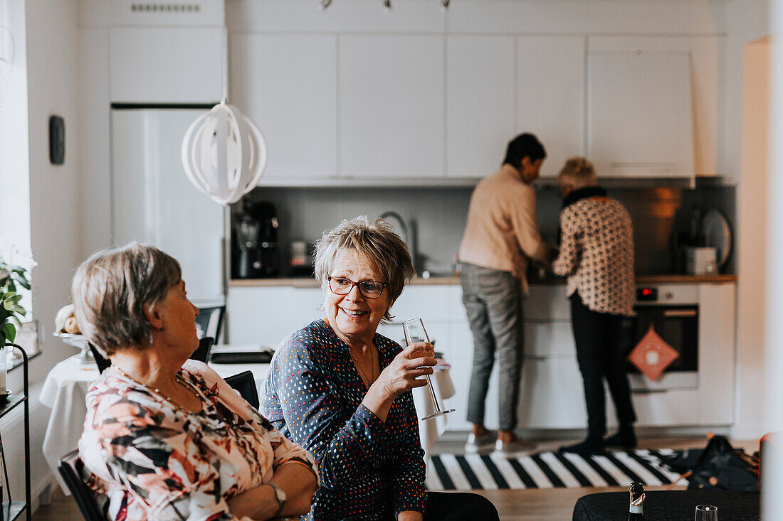 Senior friends talking together in kitchen