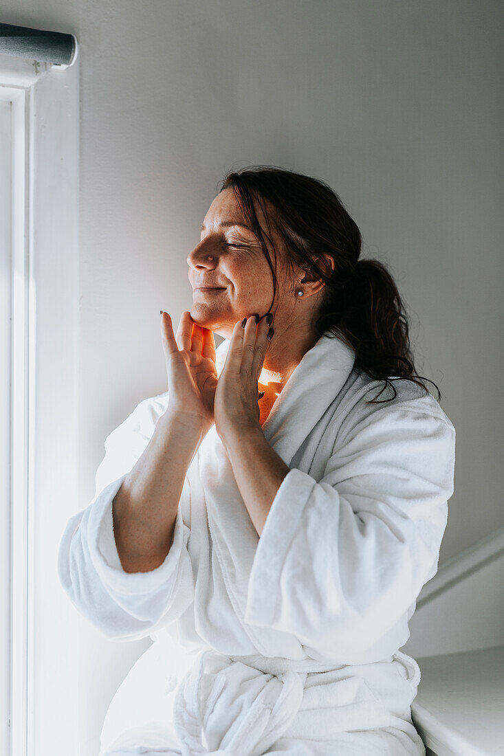 Smiling woman applying face cream