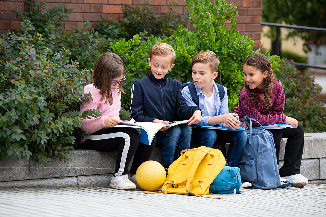 Kinder mit Schulbüchern vor dem Schulgebäude