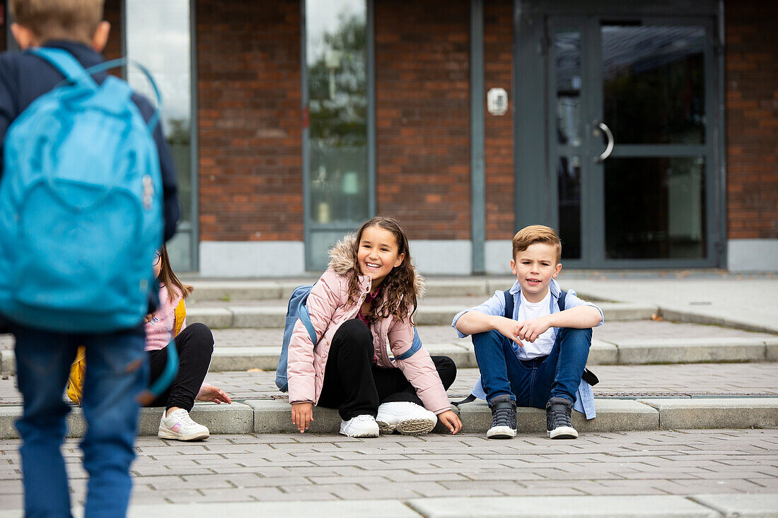 Boy and girl sitting in front of school