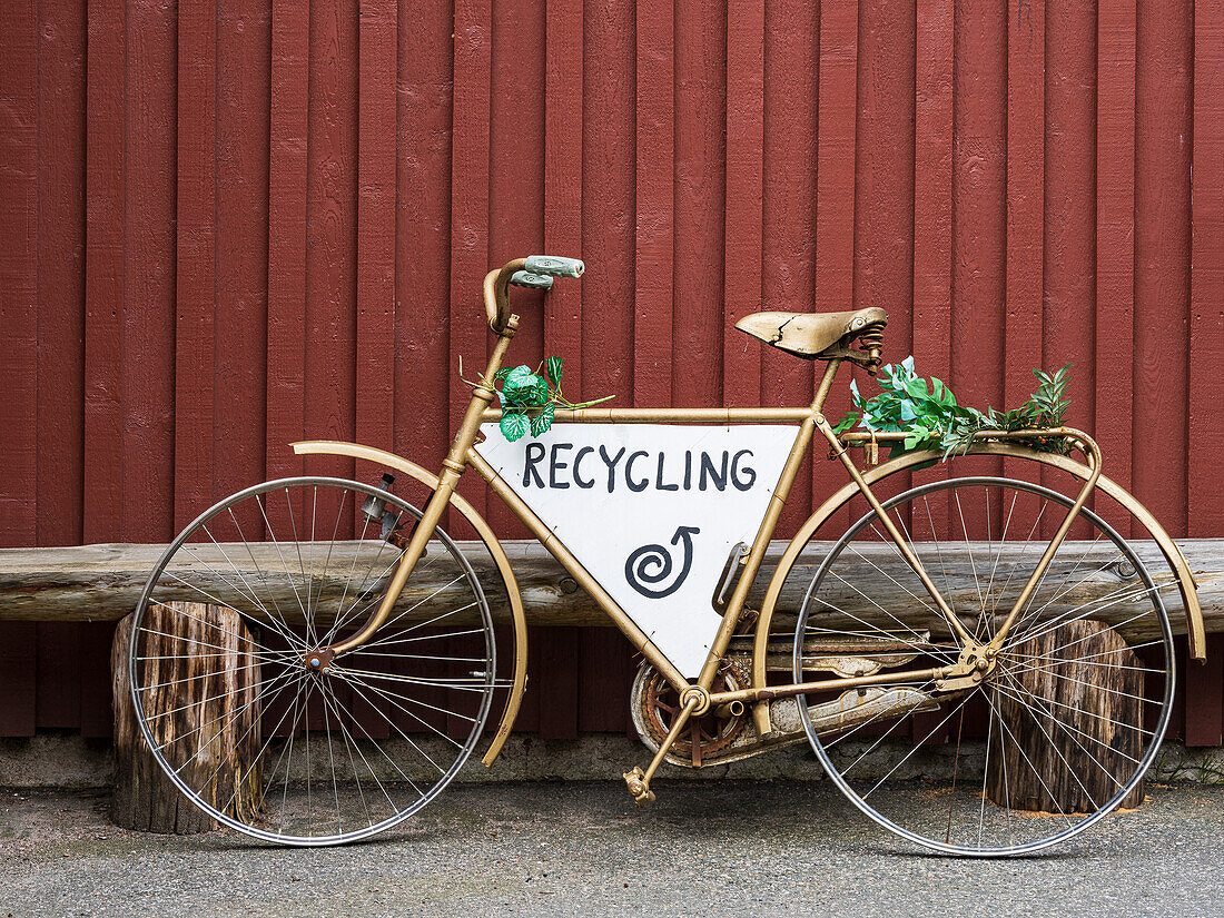 Altes Fahrrad mit Recycling-Schild an einer Holzwand