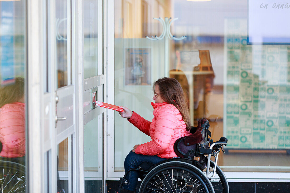 Woman on wheelchair opening door