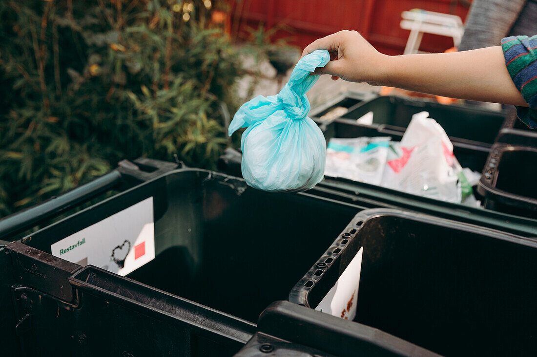 Mans hands putting plastic bag into recycling bin
