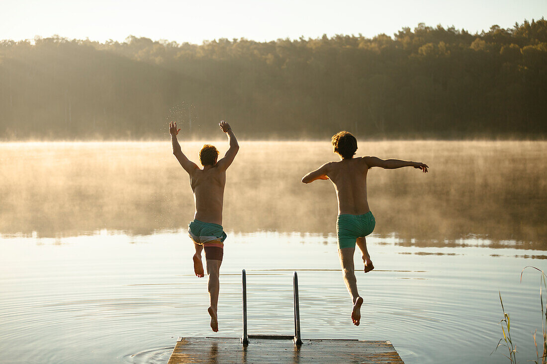 Men jumping into lake