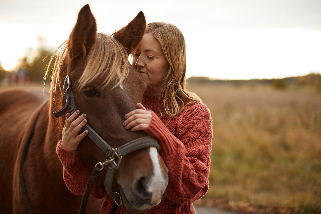 Woman stroking horse in farm