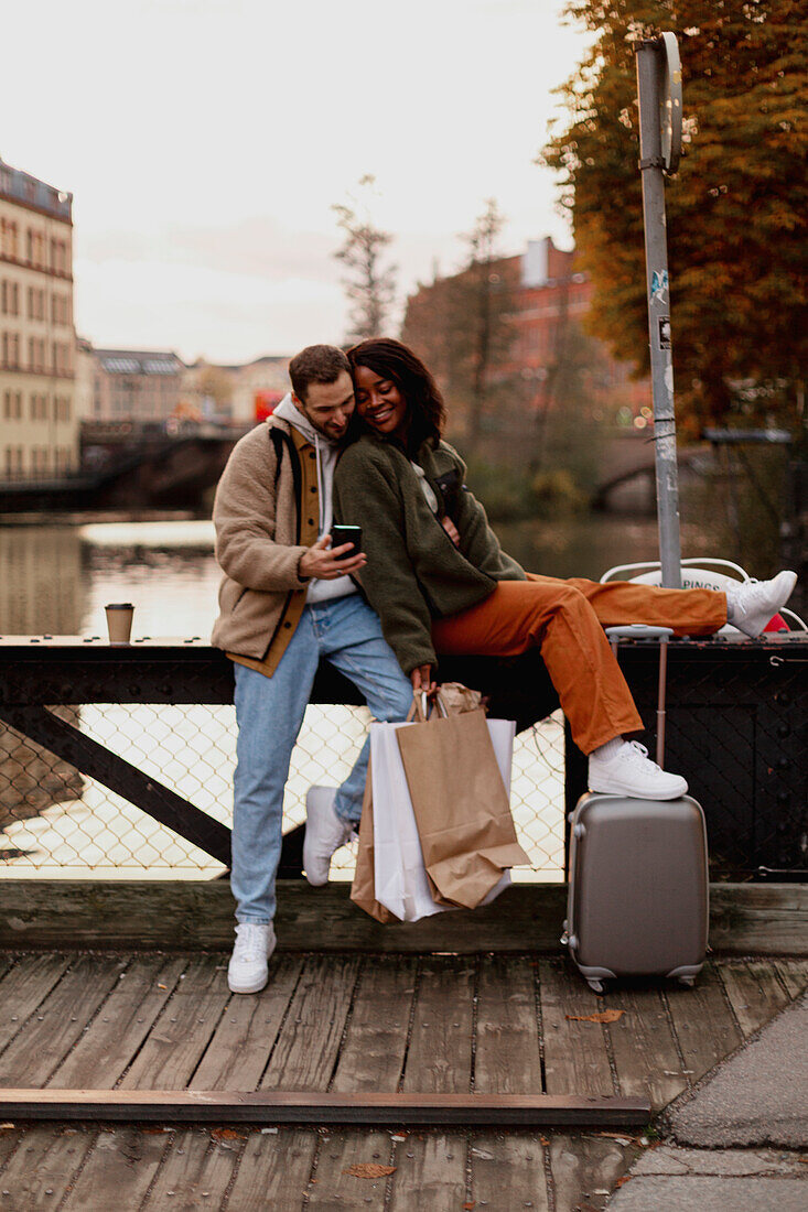 Young couple sitting near canal in town