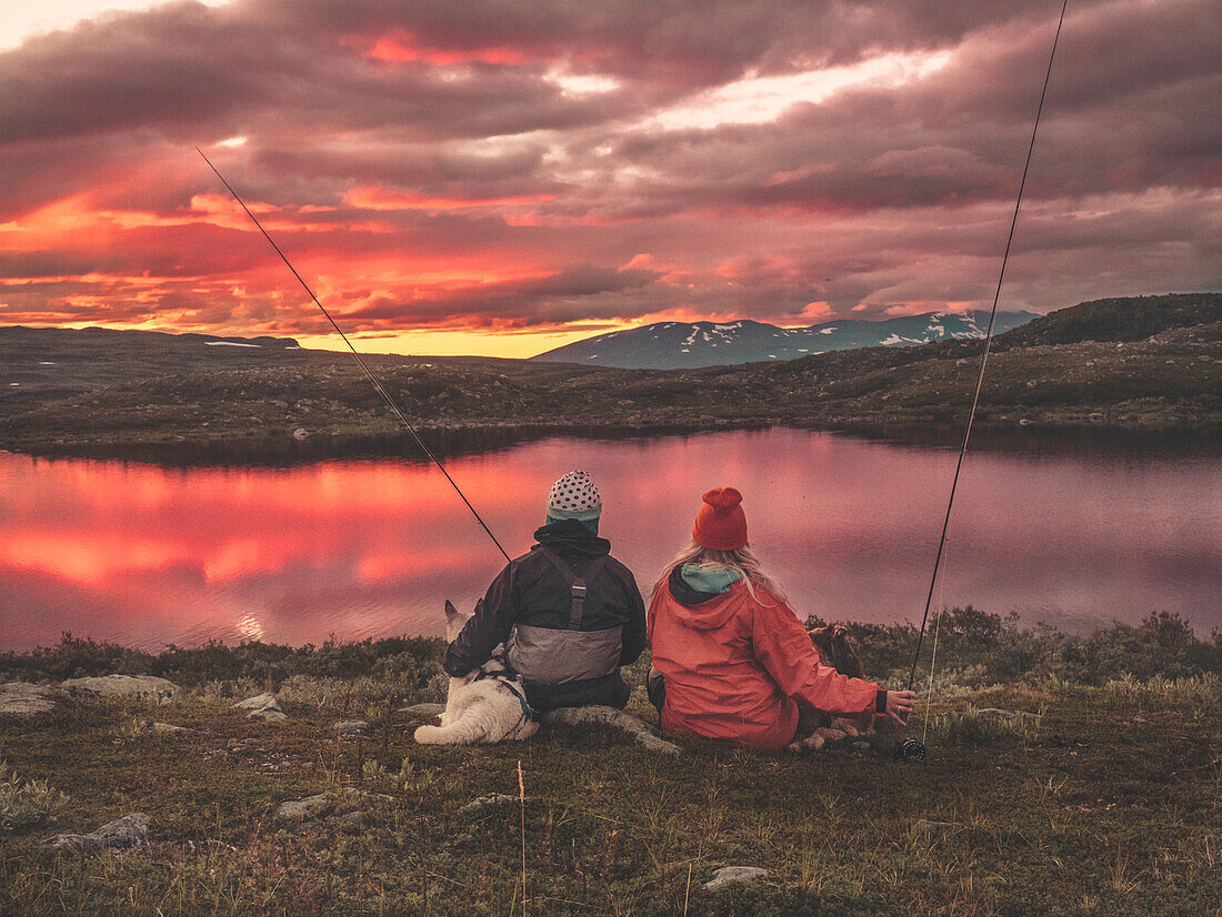 Man and woman fishing in lake at sunset