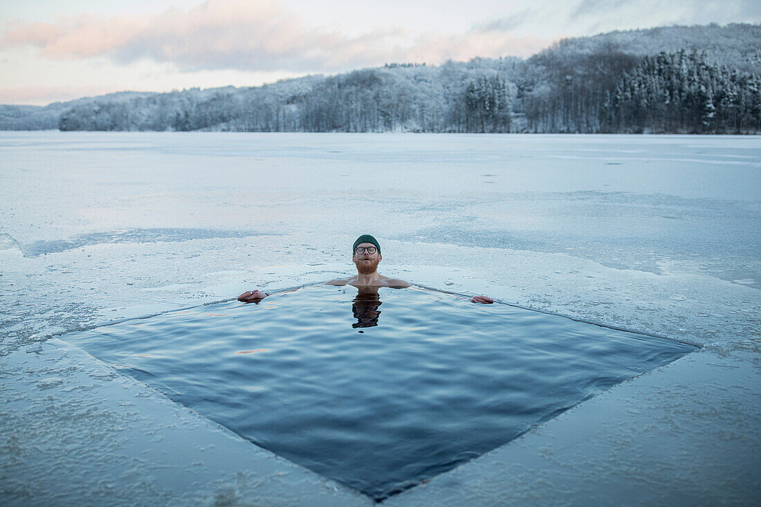 Man swimming in frozen lake