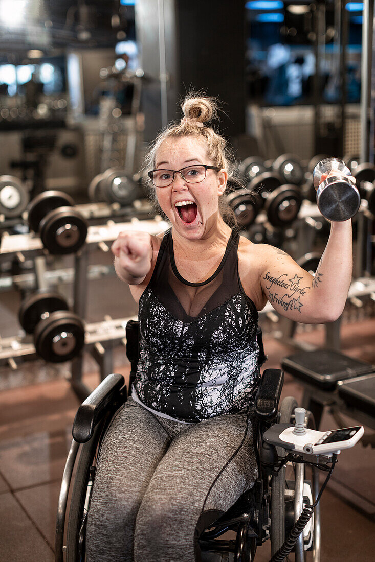 Happy woman on wheelchair training in gym