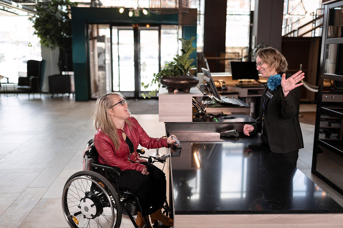 Woman on wheelchair talking to receptionist