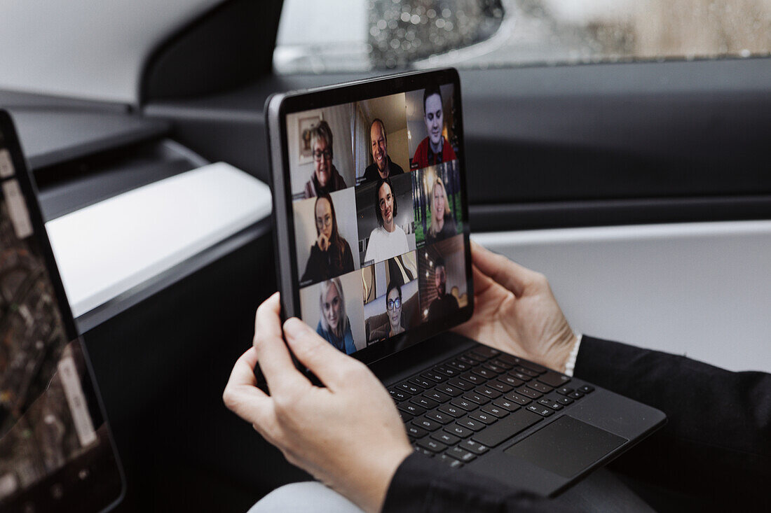 Woman in car holding laptop with video conference