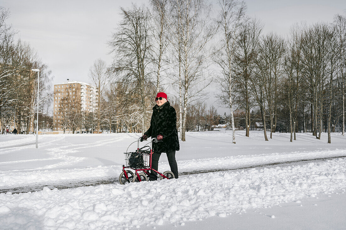 Ältere Frau mit Gehhilfe bei einem Winterspaziergang