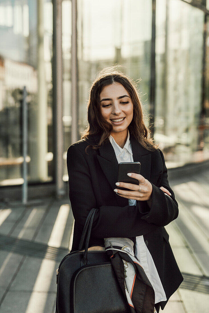 Smiling businesswoman checking cell phone