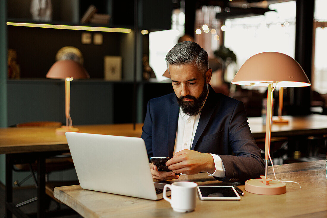 Businessman using cell phone in cafe