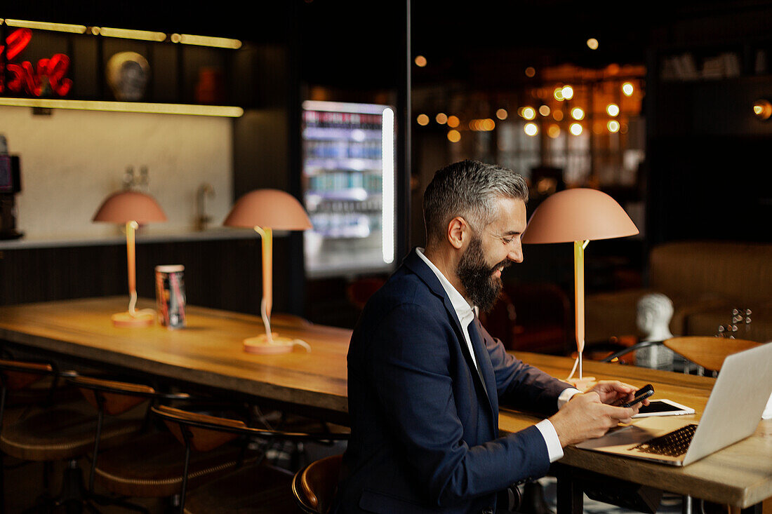 Businessman using cell phone in cafe